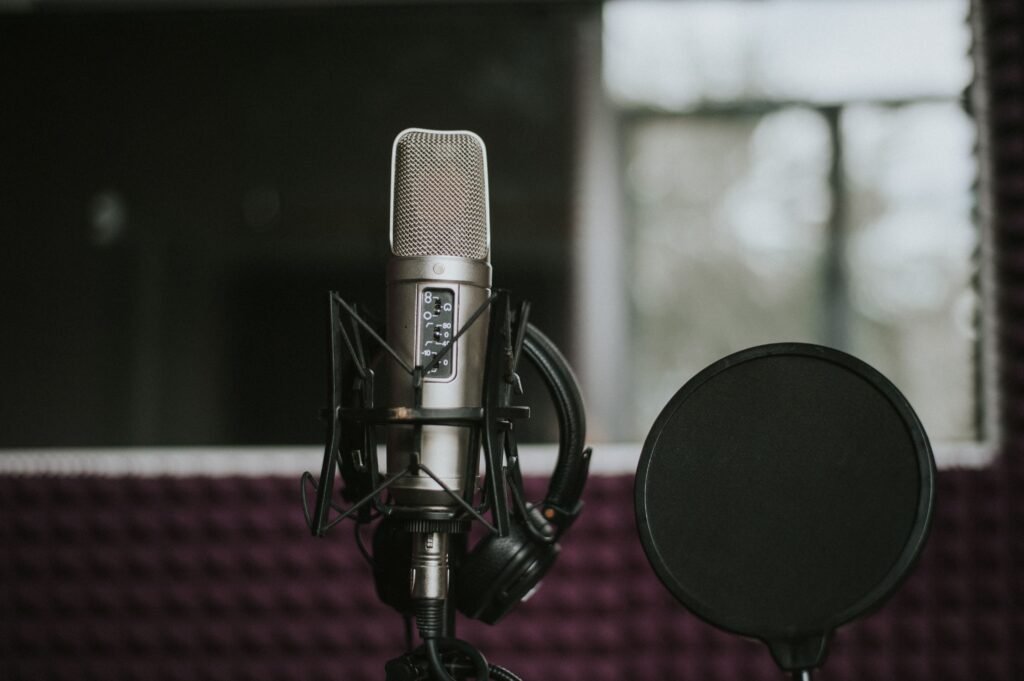 Close-up of a microphone with pop filter in a modern music studio environment.